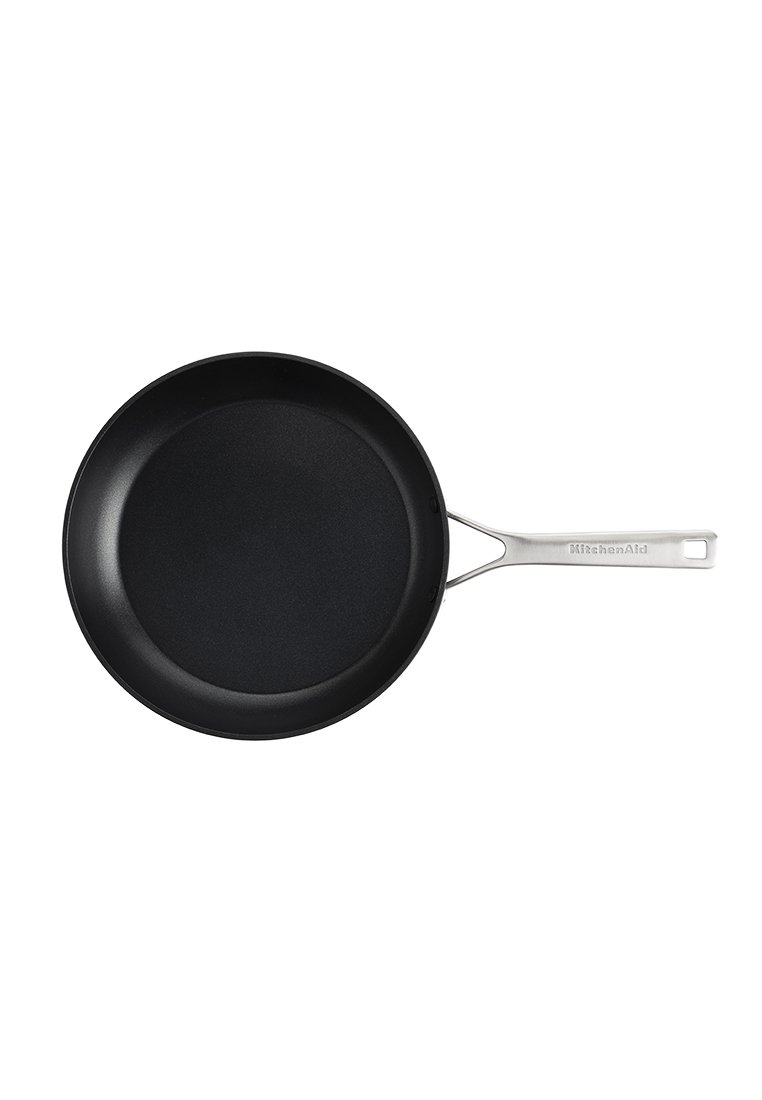 Czarna, nieprzywierająca patelnia z płaską, okrągłą powierzchnią i stalowym uchwytem. Na uchwycie znajduje się logo marki KitchenAid.