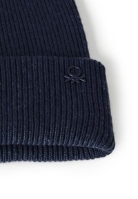 Námořnická pletená čepice s žebrovaným vzorem a ohrnutým lemem s texturovaným povrchem. Obsahuje malé, vyvýšené logo v oblasti lemu.
