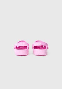 Une paire de sandales Crocs roses vues de l'arrière sur un fond gris clair uni.