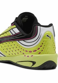 Scarpa da atletica verde e nera con tomaia testurizzata e perforazioni, accenti rosa e design elegante. Logo PUMA sul lato esterno.