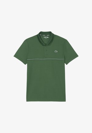 Grøn polo lavet af blødt bomuldsstof, har en klassisk krave, to knapper og et kontrasterende stribet mønster over brystet.