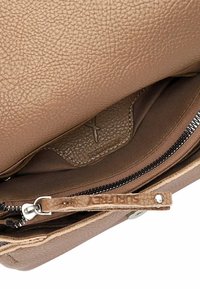 Borsa a tracolla in pelle color cognac con una texture a granuli. Presenta una tasca con zip e un rivestimento in tessuto. L'interno include un'etichetta con il logo "Supreme".