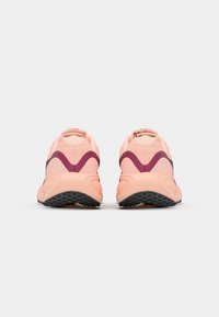Pink and maroon athletic shoes, textured mesh, curved design, cushioned sole, and black rubber outsole with tread patterns.