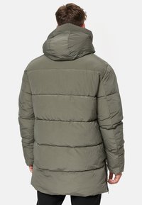 Green puffer jacket with a hood, featuring quilted sections and a durable, lightweight fabric. The back exhibits a slightly elongated cut.
