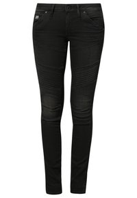Jeans skinnies de denim negro con detalles acanalados en los muslos, diseño minimalista, cinco bolsillos y cierre de cremallera con botón.