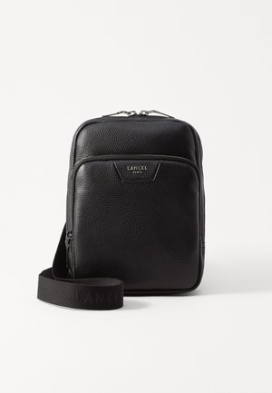 Sac en cuir noir à bandoulière avec une surface texturée, ferrures en argent, poche zippée à l'avant et sangle en tissu ajustable avec le logo "LANCEL".