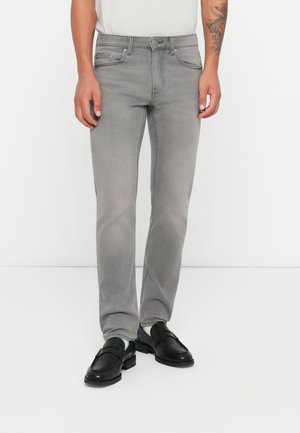 Jeans de mezclilla gris con un ajuste slim, diseño de cinco bolsillos y detalles de costura sutiles, combinados con mocasines negros.