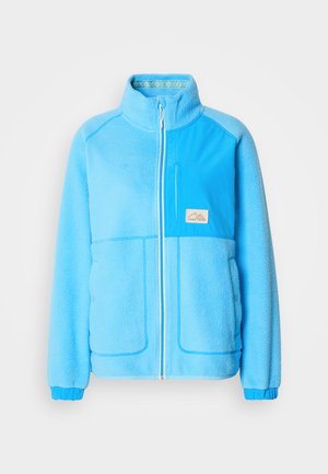 Veste en polaire bleu clair avec un col montant, fermeture éclair frontale, une poche poitrine et deux poches latérales. Poignets élastiques et accents en tissu contrasté.