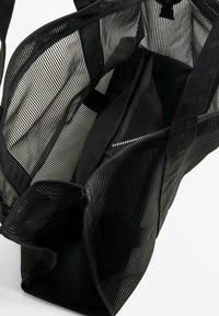 Black mesh tote bag with an open design. Features a smooth black inner compartment and dual handles for carrying. Textured exterior.