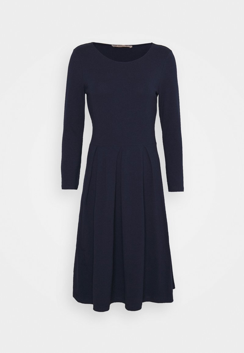Robe bleu marine à manches longues avec un col rond, encolure ajustée et jupe évasée. Fabriquée à partir d'un tissu doux et texturé avec des détails plissés.