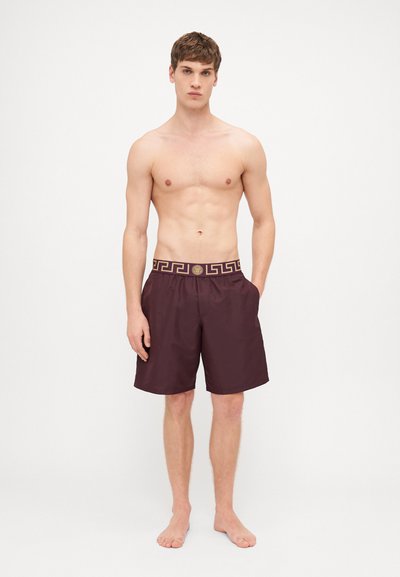 Μαρόν μαγιό σορτς με διακοσμητική χρυσή ζώνη, διαθέτοντας πλαϊνές τσέπες και άνετη εφαρμογή. Λείο υλικό, κατάλληλο για θαλάσσιες δραστηριότητες.