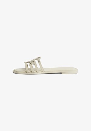 Sandalo beige piatto con tre sottili cinturini e dettaglio intrecciato sulla parte superiore, con tacco basso e suola liscia.