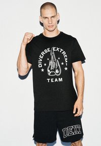 Czarny bawełniany t-shirt z grafiką rękawic bokserskich i napisem "Diverse Extreme Team" w białym kolorze, w zestawie z czarnymi szortami z napisem "DEXT."