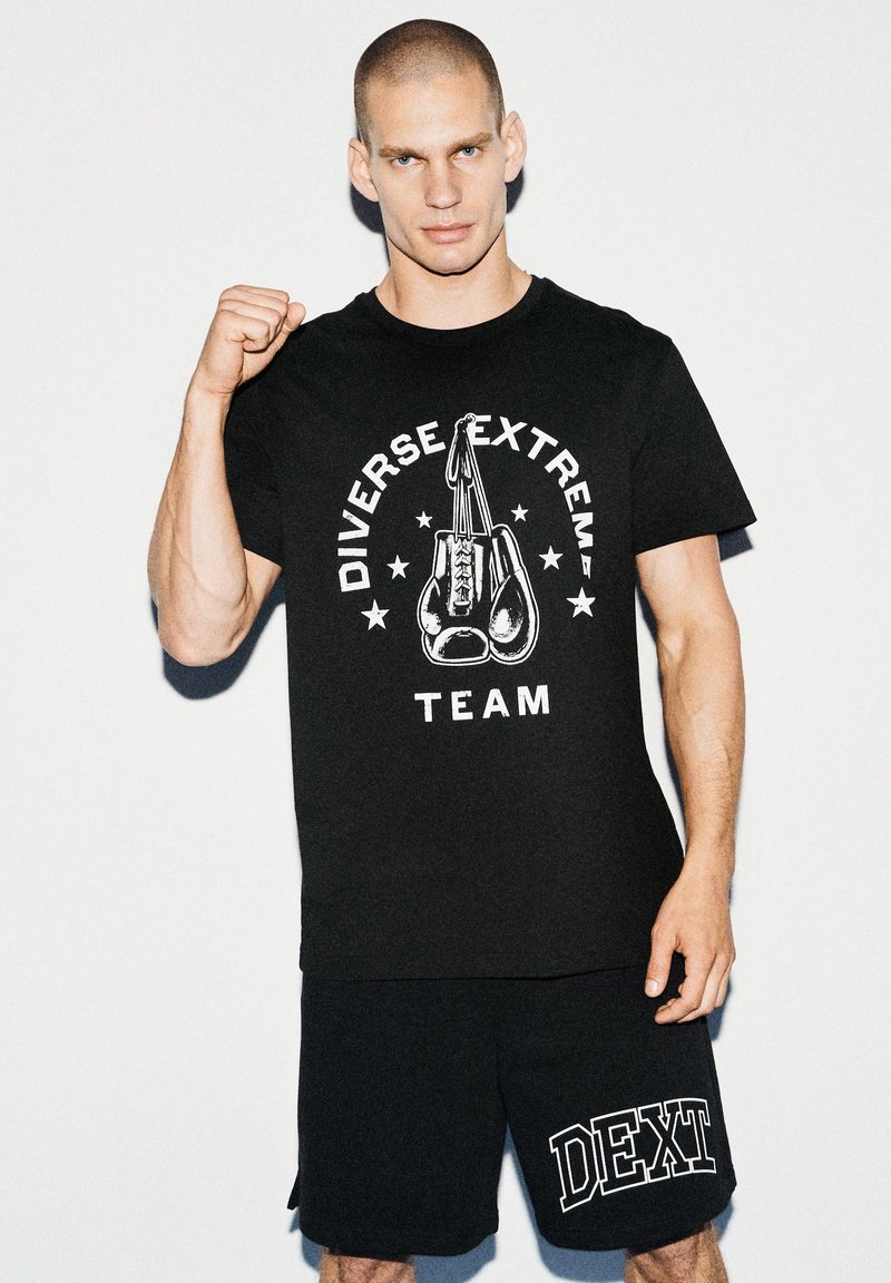 Czarny bawełniany t-shirt z grafiką rękawic bokserskich i napisem "Diverse Extreme Team" w białym kolorze, w zestawie z czarnymi szortami z napisem "DEXT."