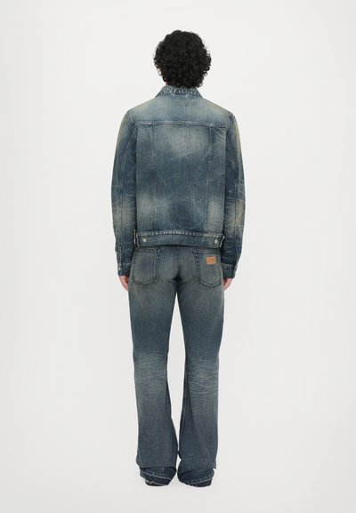 Denim jakk ja laiad teksad, mõlemad tuhm sinised. Jakk on varustatud nokk-krae ja teksadel on kaks tagumist taskut.
