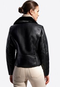 Czarna skórzana kurtka z kołnierzem z sztucznego futra, o wyraźnej konstrukcji i dopasowanym kroju. Posiada czyste szwy i subtelne detale przeszyć.