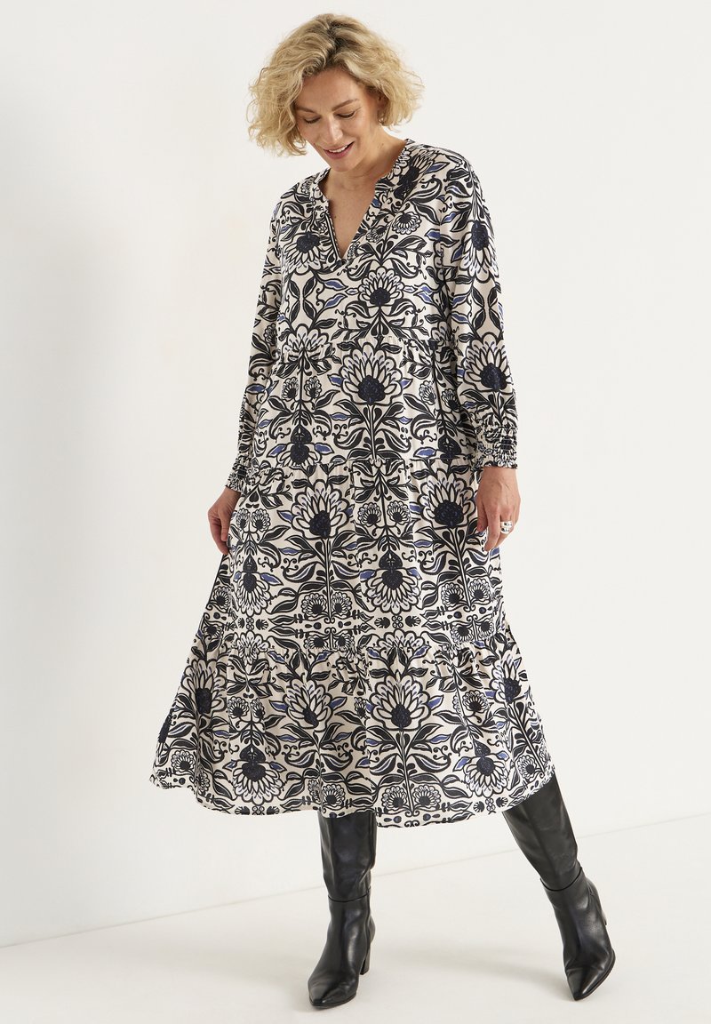 Blumenmuster-Kleid mit V-Ausschnitt, langen Ärmeln und gestuftem Rock. Die Farben umfassen marineblau, creme und blau, gefertigt aus leichtem Stoff.