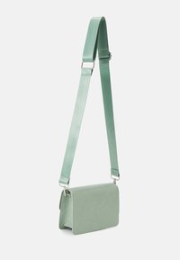 Borsa a tracolla verde menta con una finitura testurizzata in stile coccodrillo. Caratterizzata da un design piatto, cinturino regolabile e dettagli in metallo argentato.