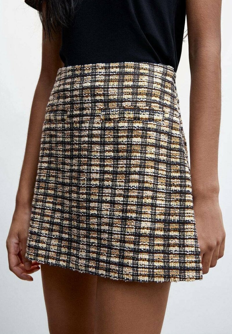 Gonna in tweed con una forma strutturata, caratterizzata da un motivo a quadri in nero, bianco e oro, vita alta e orlo leggermente svasato.