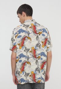 Camicia a maniche corte in tessuto crema con motivi di pesci koi colorati, nuvole blu e bamboo, dal taglio rilassato e orlo dritto.