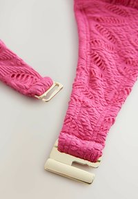 Roze gestructureerde riem met een geweven patroon, voorzien van een metalen gouden gespsluiting. Het materiaal lijkt zacht en pluche.