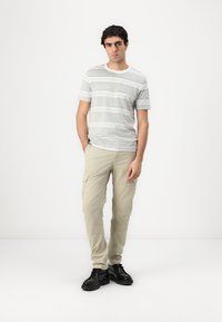 Gray and white striped t-shirt, lightweight khaki cargo pants, and black shoes. Simple design, regular fit, relaxed, durable fabric.