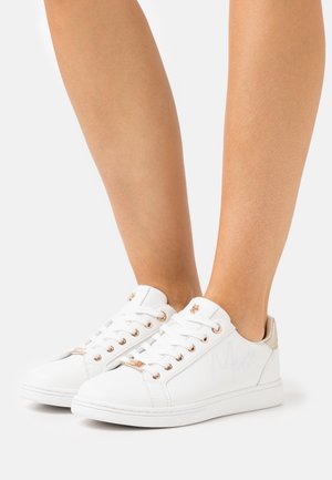 Bílé nízké tenisky z hladké kůže. Mají průchodky, tkaničky a decentní logo na boku v barvě růžového zlata. Texturovaná podrážka.