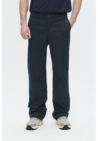Dark navy cotton trousers with a straight cut, featuring a button closure and front pockets, paired with light-colored sneakers.