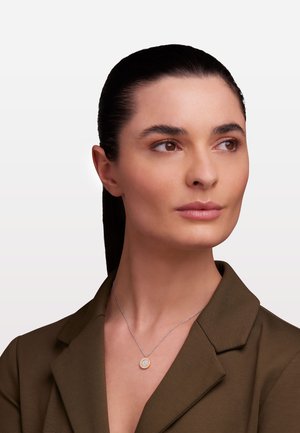 Collana in argento con pendente circolare dal superficie texturizzata color oro e gemme incorporate.