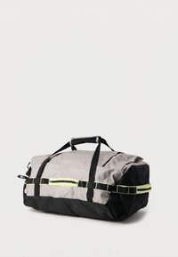 Τσάντα duffel σε γκρι και μαύρο ύφασμα, με επάνω λαβή, διπλές μαύρες ράβδους και αντανακλαστικές κίτρινες λεπτομέρειες για ορατότητα.