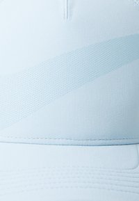 Világoskék sapka légáteresztő anyagból, texturált mintával és sima tetejével, finom vízszintes varrással.