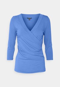 Top azul de manga larga envolvente en tejido suave, con escote en V, cintura ajustada y delicados frunces en el lateral para añadir textura.