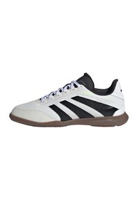Witte en zwarte low-top sportschoen met een bruine zool, witte veters en een ribbelstructuur op de bovenkant en de zool.