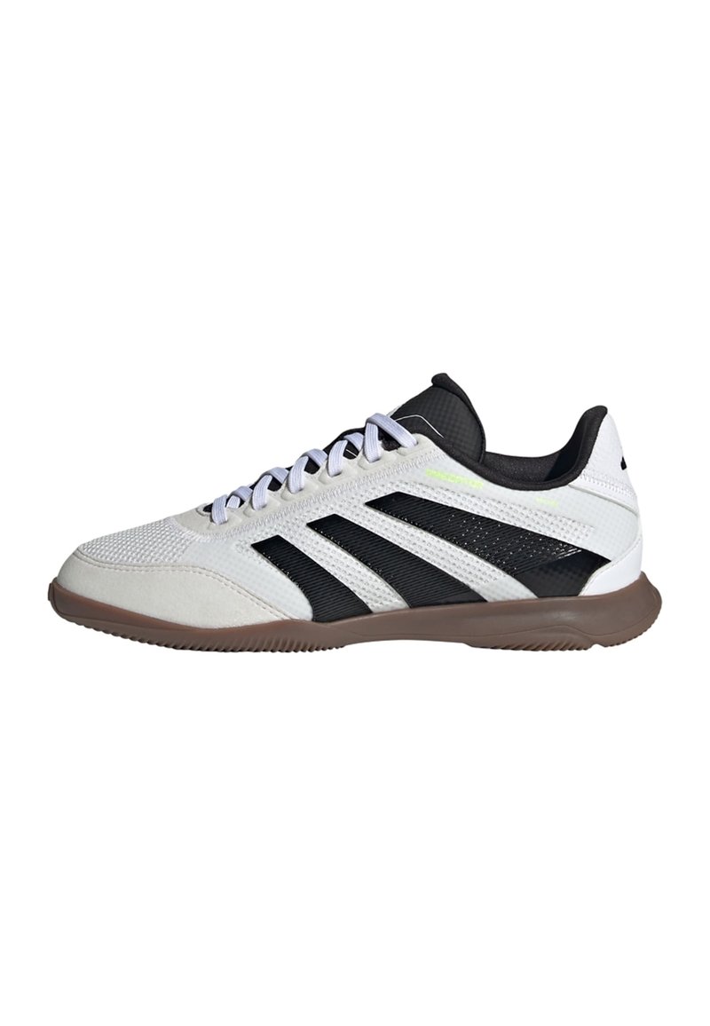 Witte en zwarte low-top sportschoen met een bruine zool, witte veters en een ribbelstructuur op de bovenkant en de zool.