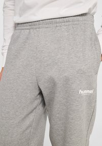 Grijze sweatpants van zachte katoen, met een elastische tailleband en zijzakken. Een wit logo is gedrukt op het onderbeen.