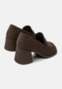 Brown suede block-heeled shoes with a rounded toe and an elastic opening. Features a subtle logo on the side and a textured sole.