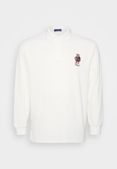 Λευκό πόλο με μακριά μανίκια, κλασικό γιακά και τρία κουμπιά, με κεντητό λογότυπο αρκούδας στο αριστερό μέρος του στήθους.