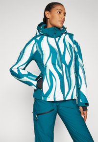 Teal ja valge puhvjakas on lainemustriga, millel on tõmblukk, eemaldatav kapuuts ja kontrastsed mustad aktsendid. Soe vatitud disain.