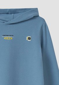 Lichtblauwe hoodie met een trekkoordcapuchon. Heeft bedrukte tekst "SOUNDTRACK OF MY LIFE VOL. 8" en een logopatch. Zachte stoftextuur.