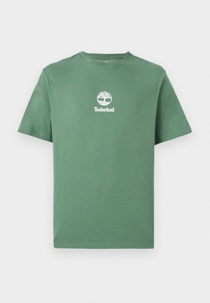 Žalia trumpomis rankovėmis suapvalintu kaklu marškinėliai su balta Timberland medžio logotipu ir tekstu, centruotu ant krūtinės.