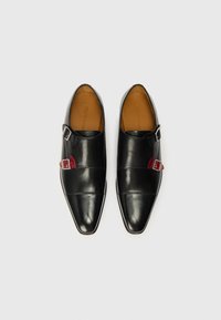 Μαύρα δερμάτινα παπούτσια με尖η μύτη, που διαθέτουν ασημένιο κούμπωμα και κόκκινη λεπτομέρεια. Λείο υφασμά και μινιμαλιστικός σχεδιασμός.