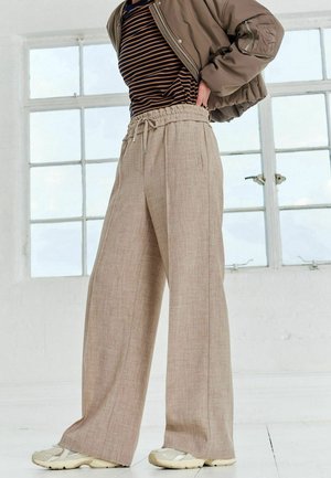 Beżowe spodnie szerokie z fakturowanym wykończeniem, z elastycznym paskiem ściąganym i bocznymi kieszeniami. Luźny krój o prostym fasonie.