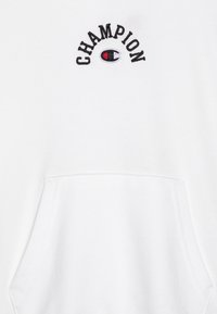 Vit sweatshirts med en framficka, broderad "CHAMPION"-logotyp i svart och rött, med en jämn, strukturerad tyg.