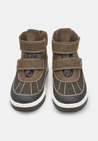 Cizme de iarnă din suede maro și material sintetic, cu două curele cu arici, căptușeală din blană, cusături albe și talpă texturată din cauciuc negru.