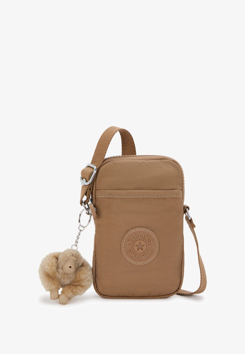 Malá hnědá crossbody taška s logem Kipling, nastavitelného popruhu a připojeným plyšovým klíčenkovým opičkem.