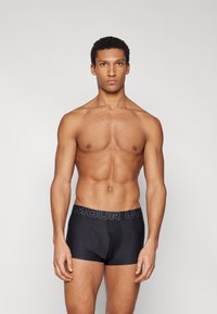 Zwarte boxershorts van rekbaar materiaal, met een aansluitend ontwerp en een brede elastische tailleband waarop de merknaam in grijs staat.