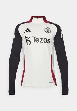White long-sleeve training top with black sleeves, a quarter zip collar, red accents, Manchester United logo, and Tezos branding on the front.