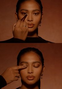 Makeup-applikasjonsscene med en modell med jevn, strålende hud, definerte øyenbryn og glansfulle lepper, mot en varm brun bakgrunn.