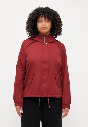 Red lightweight jacket with a zipped front, hood, elastic cuffs, two side pockets, and drawstrings at the hem. Smooth fabric texture.
