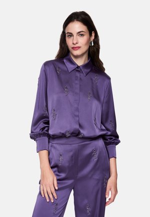 Purple satin blouse with a collared neckline, featuring embroidered embellishments. Long sleeves with elastic cuffs, paired with matching trousers.